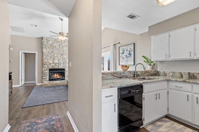 kitchen featuring sink, dark wood-type flooring, dishwasher, white cabinetry, and a stone fireplace