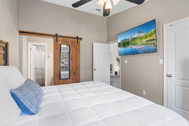 bedroom featuring connected bathroom, a barn door, and ceiling fan