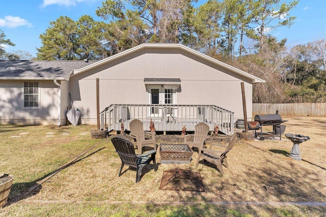 rear view of house with french doors, a wooden deck, a yard, and an outdoor fire pit