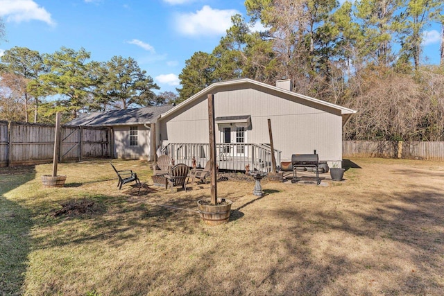 rear view of house with a wooden deck and a yard