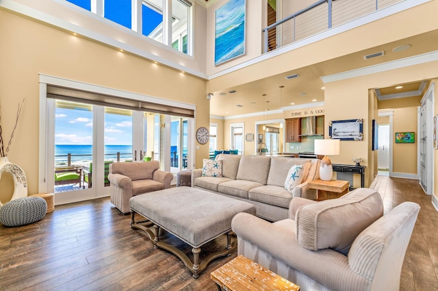 living room with a water view, wood-type flooring, a high ceiling, and ornamental molding