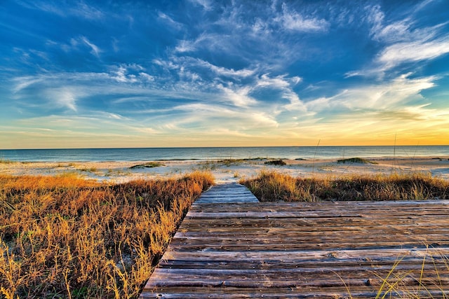 view of dock featuring a beach view and a water view