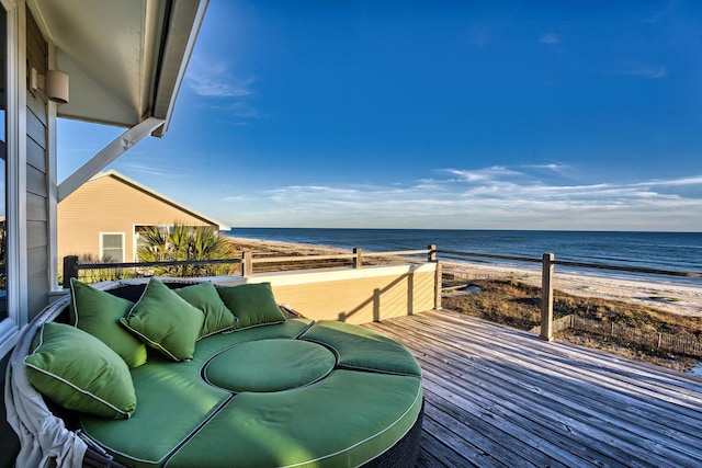 wooden deck featuring outdoor lounge area, a water view, and a beach view