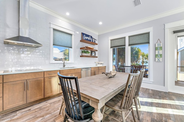 dining space with light wood-type flooring, ornamental molding, and sink