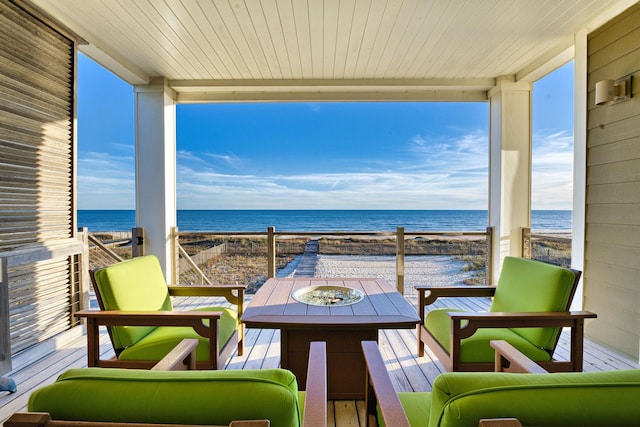 balcony with a beach view, a water view, and an outdoor fire pit