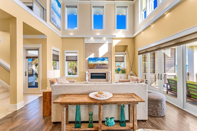 living room with crown molding, dark wood-type flooring, a high ceiling, and french doors