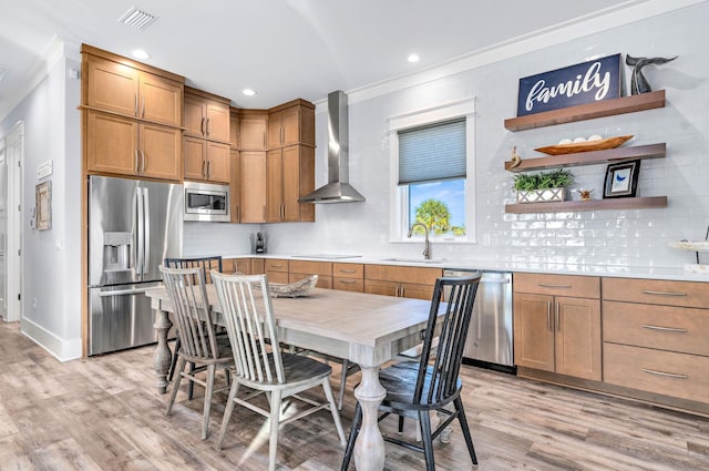 kitchen with light hardwood / wood-style floors, sink, wall chimney range hood, and stainless steel appliances