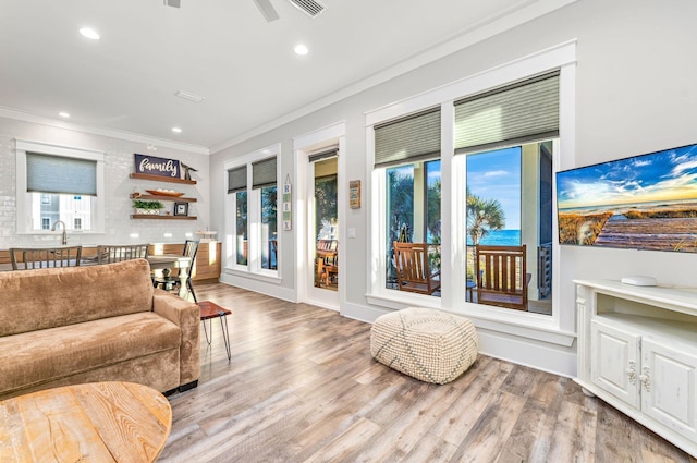 living room featuring a healthy amount of sunlight, crown molding, ceiling fan, and light hardwood / wood-style floors