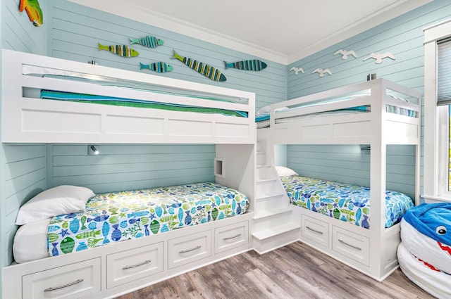 bedroom featuring wooden walls, hardwood / wood-style flooring, and crown molding