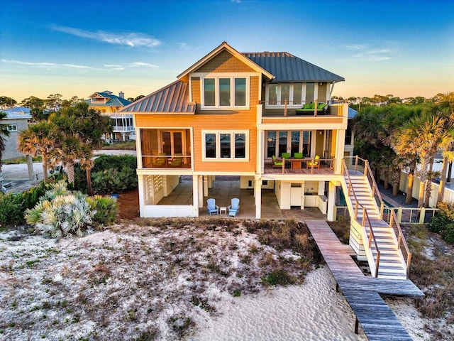 back house at dusk featuring a balcony and a patio area