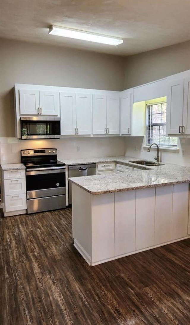 2585 Panther Creek Rd, Tallahassee, FL 32308 - kitchen with stainless steel appliances, a peninsula, light stone counters, white cabinetry, and dark wood-style flooring