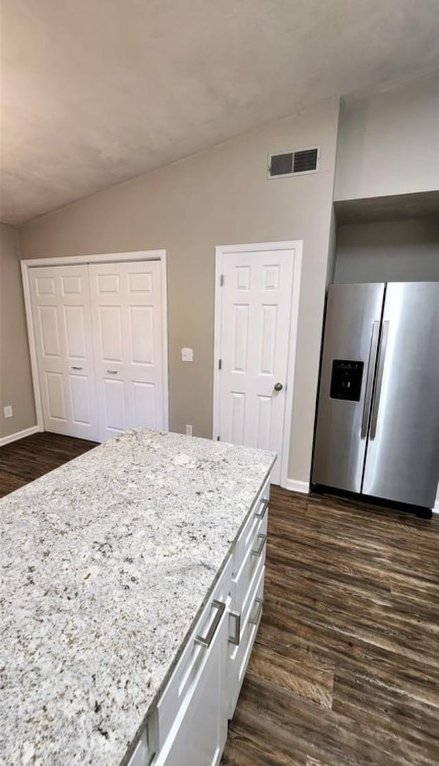 2585 Panther Creek Rd, Tallahassee, FL 32308 - kitchen featuring stainless steel fridge, lofted ceiling, dark wood finished floors, light stone counters, and white cabinets