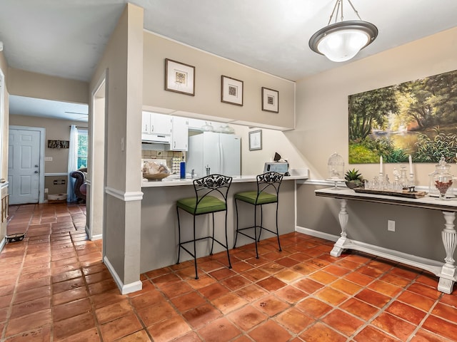 3104 Oak Hammock Ln Unit U, Tallahassee, FL 32301 - kitchen with freestanding refrigerator, tile patterned floors, white cabinets, a breakfast bar, and light countertops