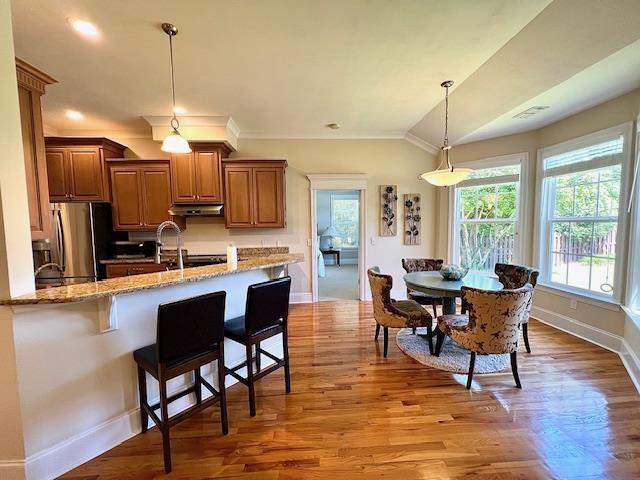 2541 Lagrange Trl, Tallahassee, FL 32312 - kitchen with freestanding refrigerator, under cabinet range hood, baseboards, light stone countertops, and a kitchen bar