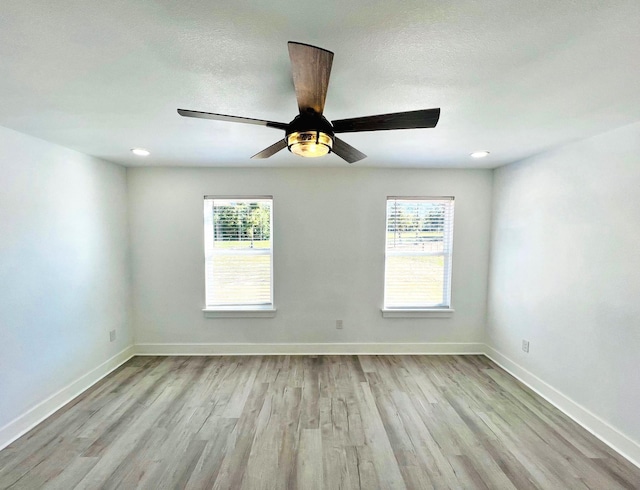 unfurnished room featuring ceiling fan, a healthy amount of sunlight, light wood-type flooring, and a textured ceiling