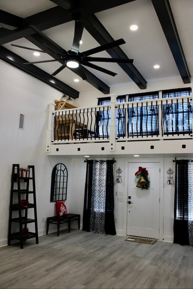 entrance foyer with beam ceiling, hardwood / wood-style flooring, ceiling fan, and a high ceiling