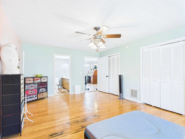 3696 Joel Aman Rd, Perry, FL 32347 - bedroom featuring light wood-style flooring, two closets, a textured ceiling, ensuite bathroom, and a ceiling fan
