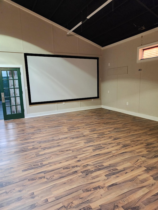 home theater room with hardwood / wood-style floors and vaulted ceiling