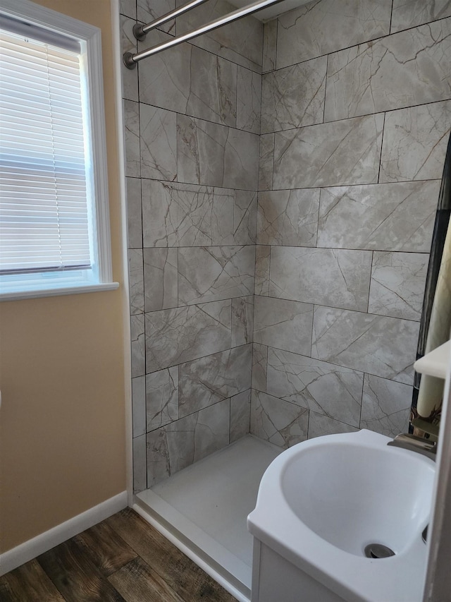 bathroom with a tile shower and hardwood / wood-style floors