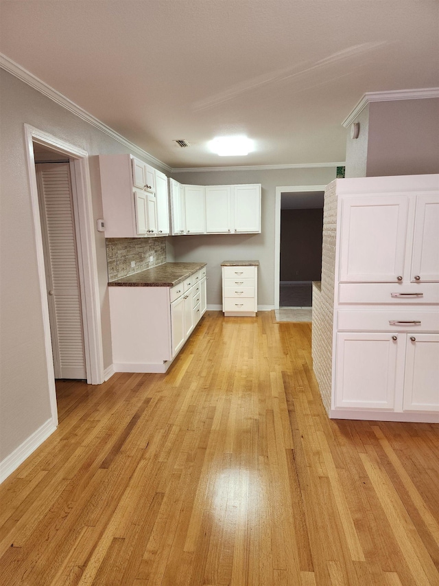 kitchen featuring white cabinetry, ornamental molding, light hardwood / wood-style flooring, and backsplash