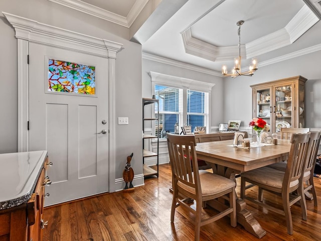 dining space featuring an inviting chandelier, dark hardwood / wood-style floors, a raised ceiling, and crown molding