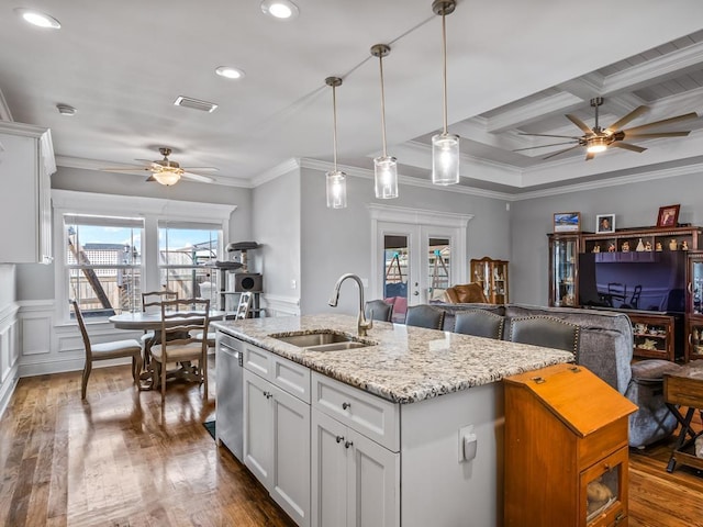 kitchen featuring hanging light fixtures, white cabinetry, sink, and a kitchen island with sink