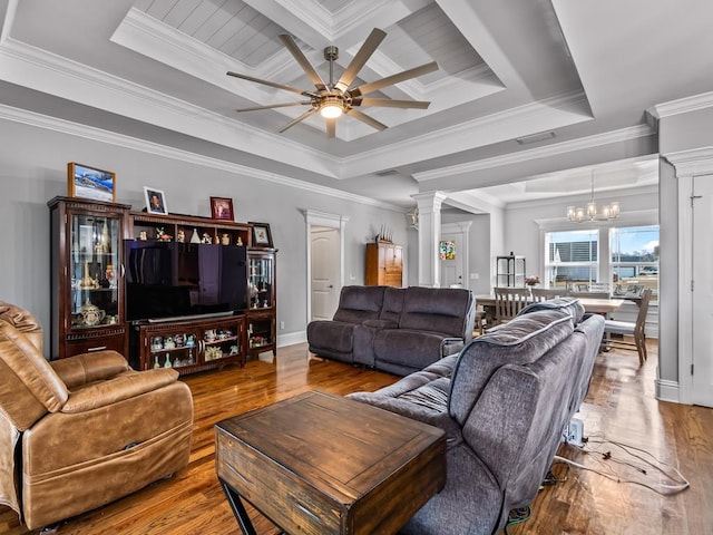 living room with ceiling fan with notable chandelier, hardwood / wood-style floors, decorative columns, a tray ceiling, and crown molding