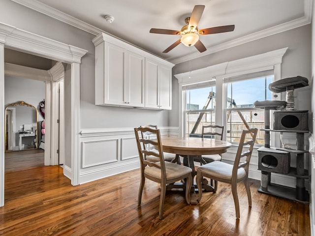 dining area featuring dark hardwood / wood-style flooring, crown molding, and ceiling fan