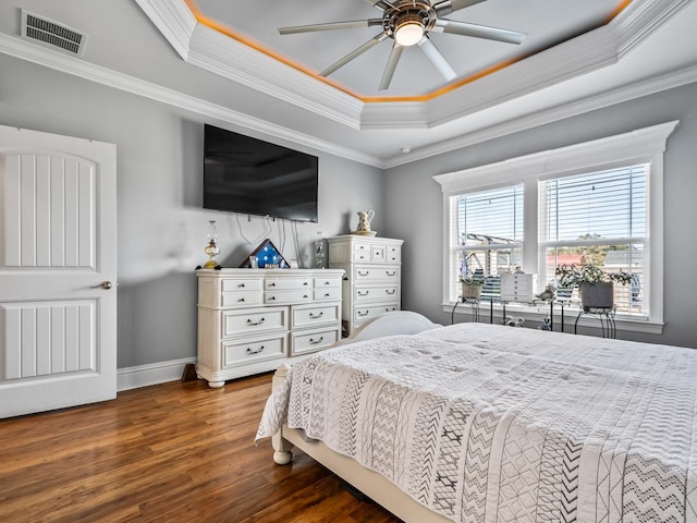 bedroom with dark hardwood / wood-style floors, ceiling fan, a tray ceiling, and crown molding