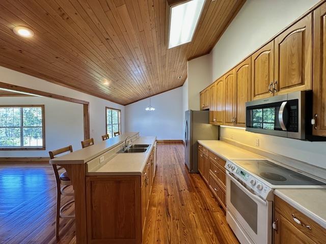 kitchen with a center island with sink, lofted ceiling, stainless steel appliances, sink, and a breakfast bar area