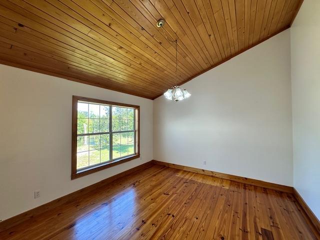 spare room featuring lofted ceiling, an inviting chandelier, ornamental molding, wooden ceiling, and wood-type flooring