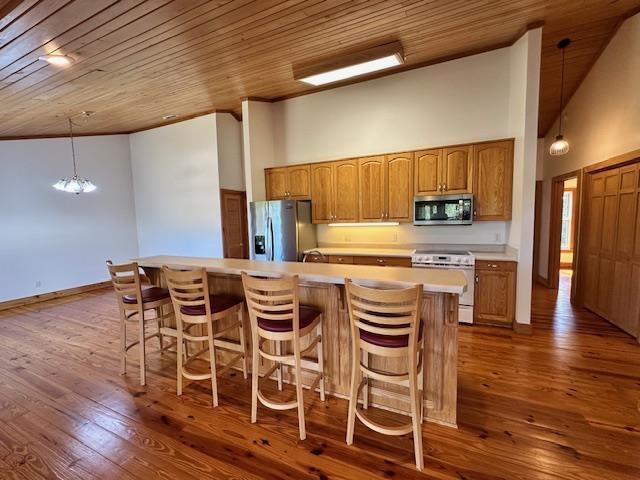 kitchen with dark hardwood / wood-style flooring, decorative light fixtures, a kitchen island, an inviting chandelier, and appliances with stainless steel finishes