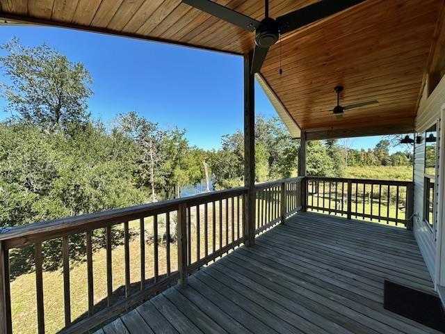 wooden deck with a water view and ceiling fan