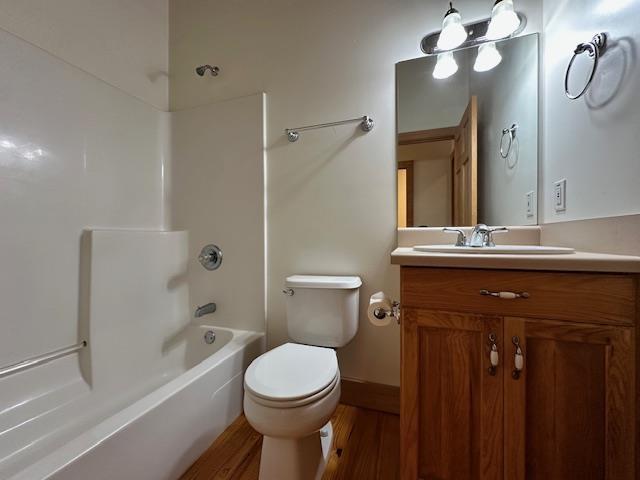 full bathroom with hardwood / wood-style flooring, vanity, toilet, and washtub / shower combination