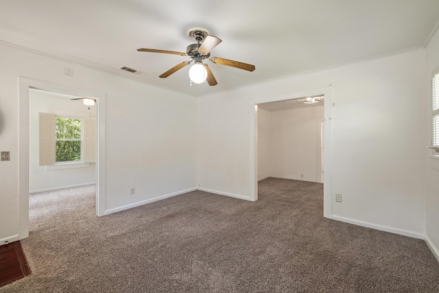 carpeted empty room featuring a ceiling fan, ornamental molding, and baseboards