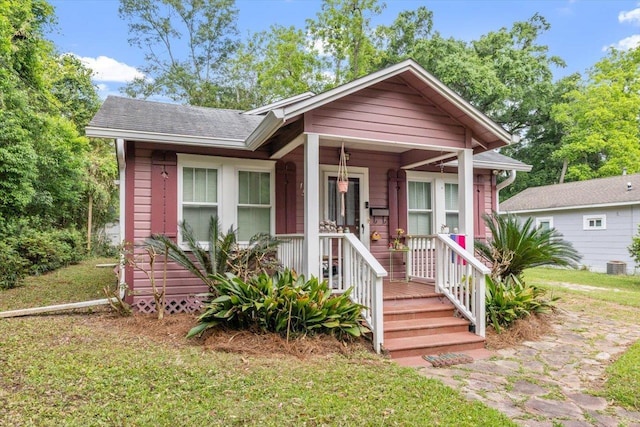 bungalow-style home with roof with shingles, cooling unit, and a front yard