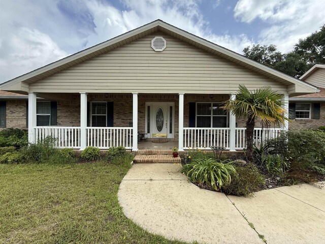 601 Judson Dr, Perry, FL 32348 - view of front of house featuring brick siding, a porch, and a front yard
