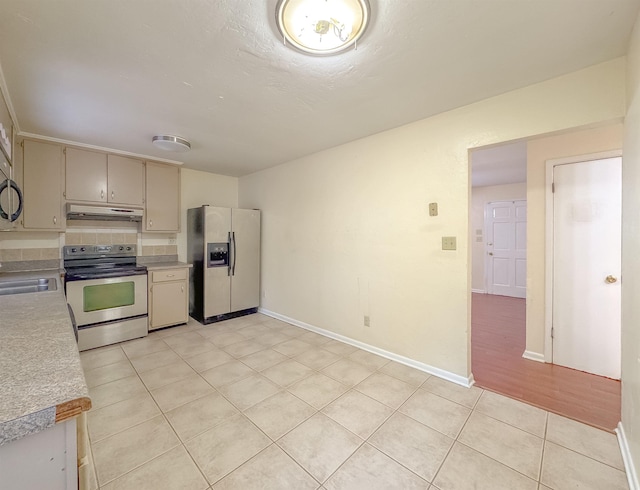 kitchen with a sink, light countertops, under cabinet range hood, light tile patterned floors, and appliances with stainless steel finishes