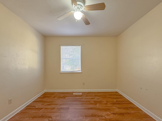 spare room with light wood-type flooring, visible vents, a ceiling fan, and baseboards