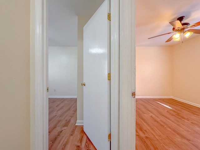 hall featuring light wood-style flooring and baseboards