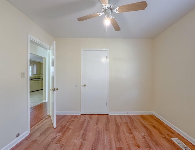 unfurnished bedroom with a ceiling fan, visible vents, light wood-style floors, and baseboards