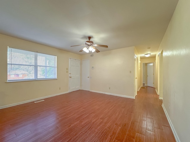 empty room with baseboards, a ceiling fan, visible vents, and light wood-style floors