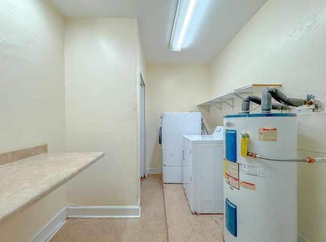 clothes washing area featuring separate washer and dryer, laundry area, a textured wall, and water heater