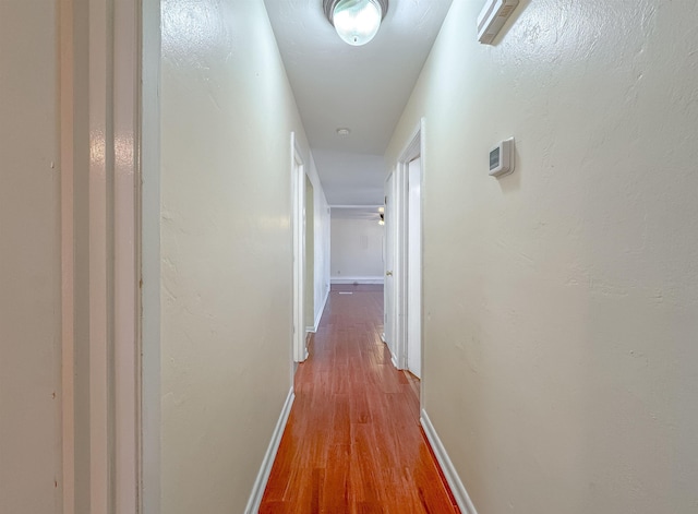 hall with baseboards and wood finished floors