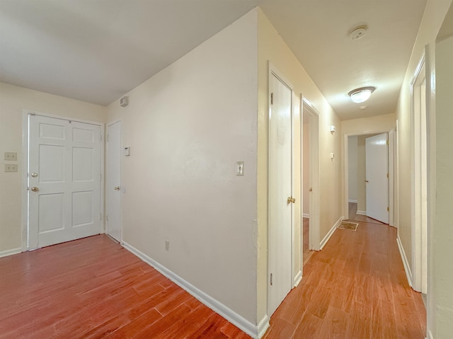 hall with baseboards and light wood-style floors