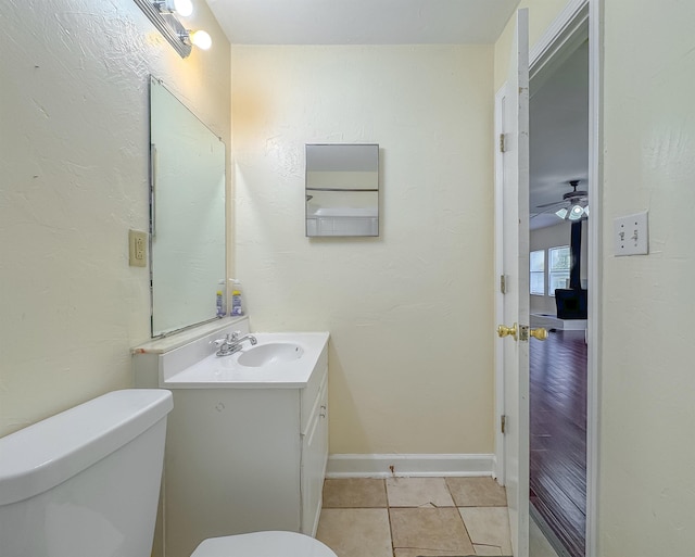 half bath featuring ceiling fan, baseboards, toilet, vanity, and tile patterned flooring