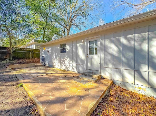 view of side of home with fence, a patio, and board and batten siding