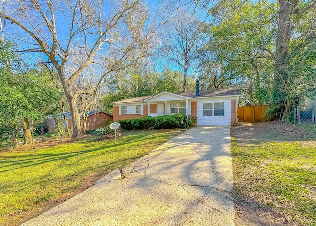 ranch-style house featuring brick siding, fence, driveway, and a front lawn