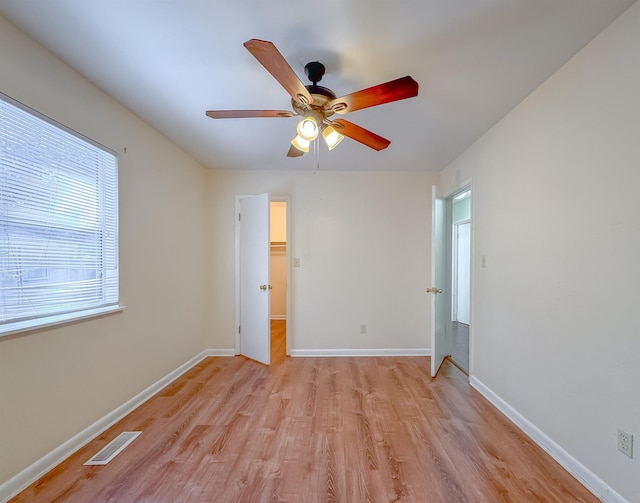 spare room with ceiling fan, visible vents, baseboards, and light wood-type flooring