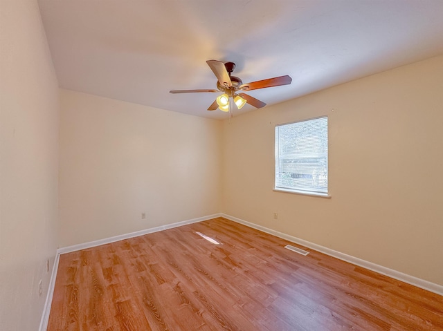 empty room featuring light wood-style flooring, visible vents, baseboards, and ceiling fan